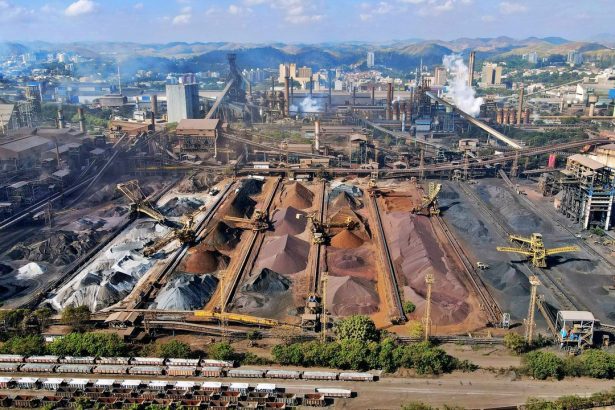 Vista ampla de uma instalação mineradora industrial, com máquinas, estruturas de processamento e pilhas de resíduos minerais.