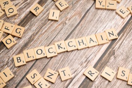 Letras de madeira formando a palavra “blockchain” sobre uma superfície de madeira.