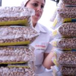 Trabalhadora organiza sacos de feijão em uma unidade de processamento e distribuição de alimentos.