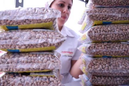 Trabalhadora organiza sacos de feijão em uma unidade de processamento e distribuição de alimentos.